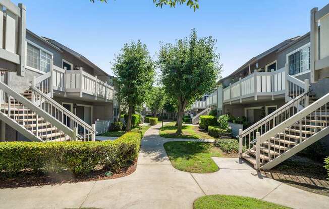 A sunny day at a residential complex with a pathway and greenery.