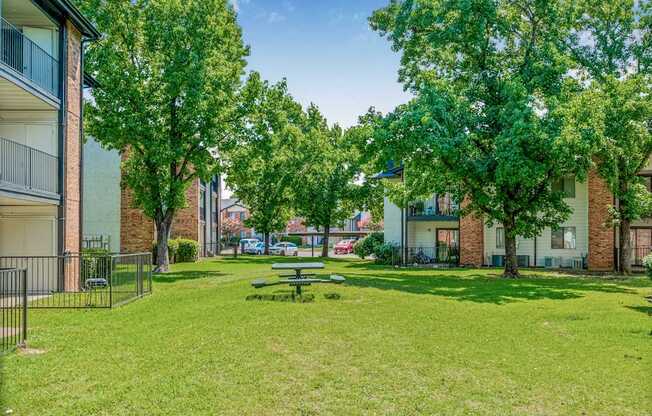 A park with a picnic table surrounded by trees and buildings.