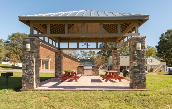 a pavilion with two picnic tables and a grill