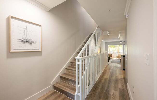 A drawing of a sailboat is hanging on a wall above a staircase.