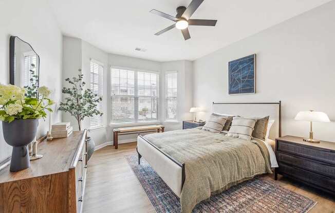 A bedroom with a bed, a ceiling fan, and a wooden dresser.