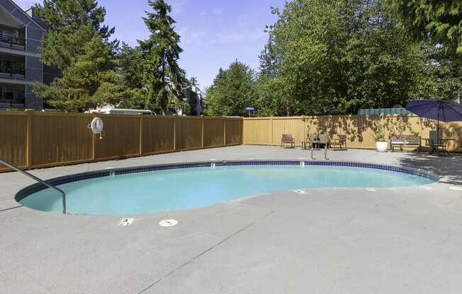 a pool with a fence around it and trees in the background at Casa Blanca Apartment Homes, Everett, 98204