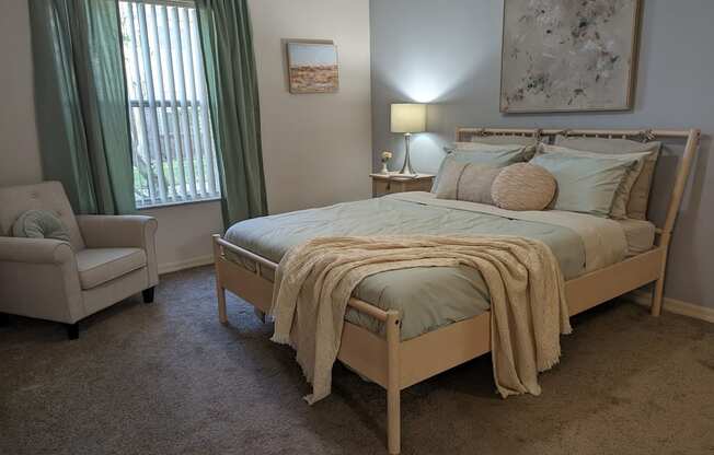 a bedroom with a bed and a chair and a window