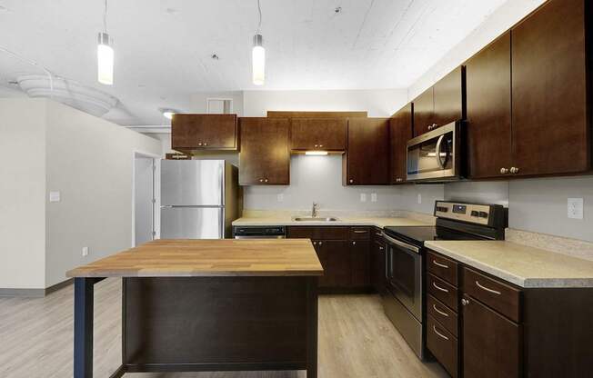 A kitchen with a wooden island and stainless steel appliances.
