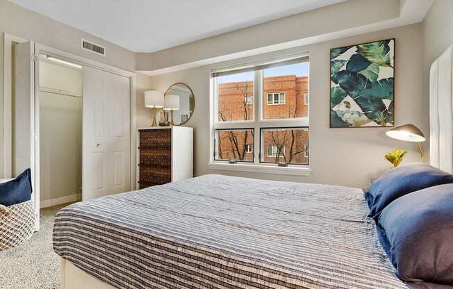 A bedroom with a large bed and a window overlooking a brick building.