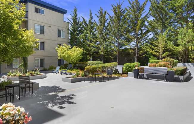 a seating area with benches and trees in front at Guinevere Apartment Homes, WA 98103