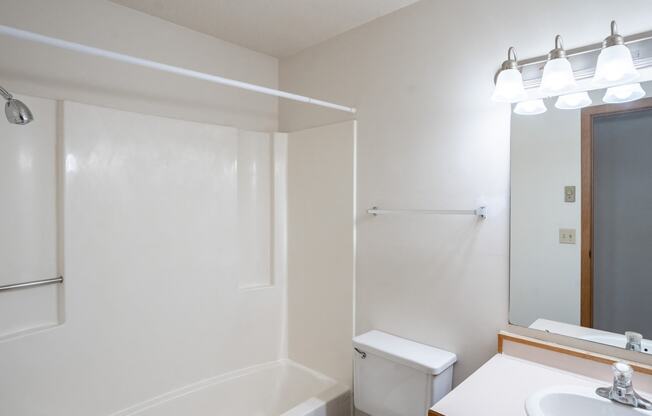 a bathroom with a toilet and a sink and a mirror. Fargo, ND Westview Towers Apartments