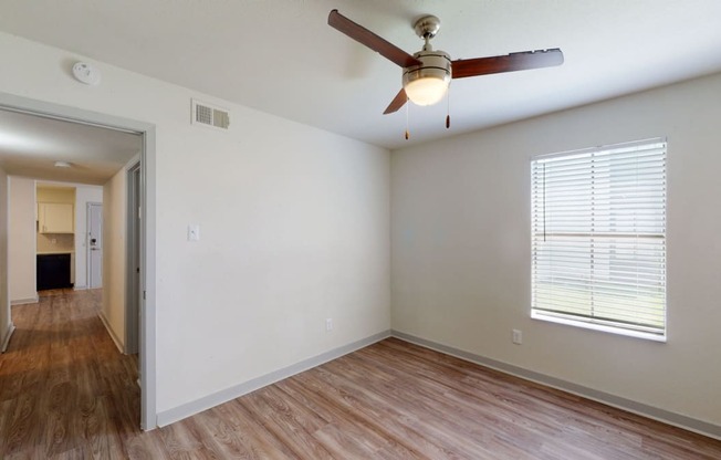 an empty living room with a ceiling fan and a large window