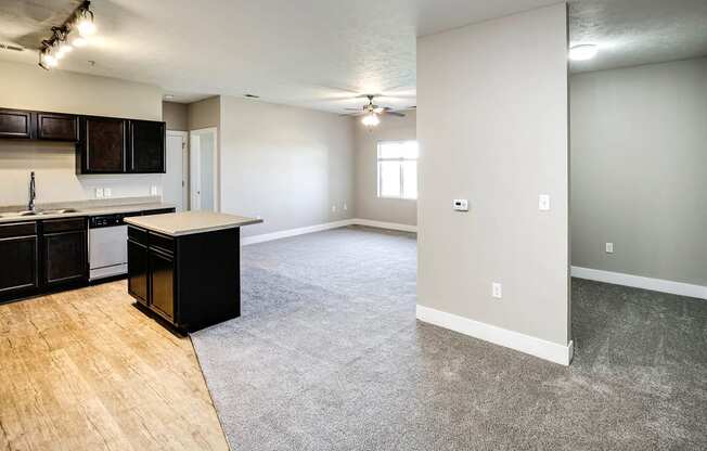 an empty living room with an empty kitchen with an island in the middle