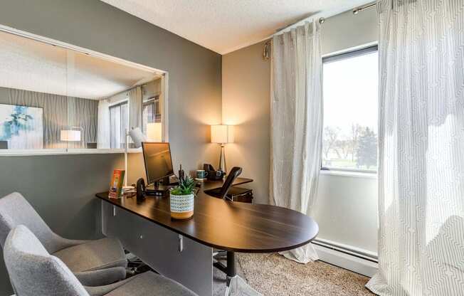 a desk with a computer and a chair in a room with a large window  at ReNew at Neill Lake, Eden Prairie