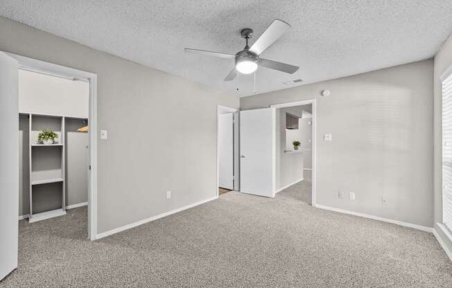 A room with a ceiling fan and carpeted floor.