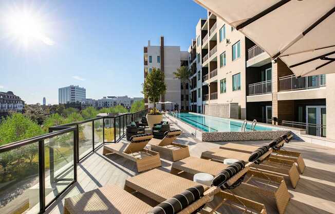A sunny day at the rooftop pool and lounging area of a modern apartment complex.