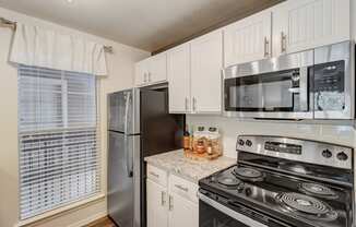 an updated kitchen with stainless steel appliances and white cabinets
