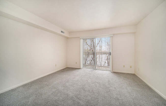 A living room with a carpeted floor and a slider to a private balcony at Brentwood Park Apartments, La Vista, Nebraska