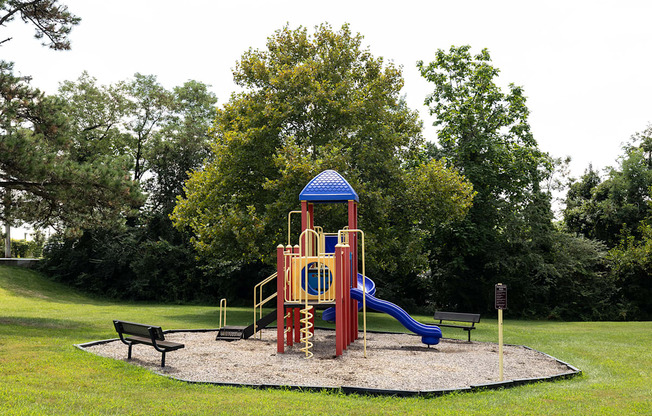 A playground with a blue and yellow structure and a slide.