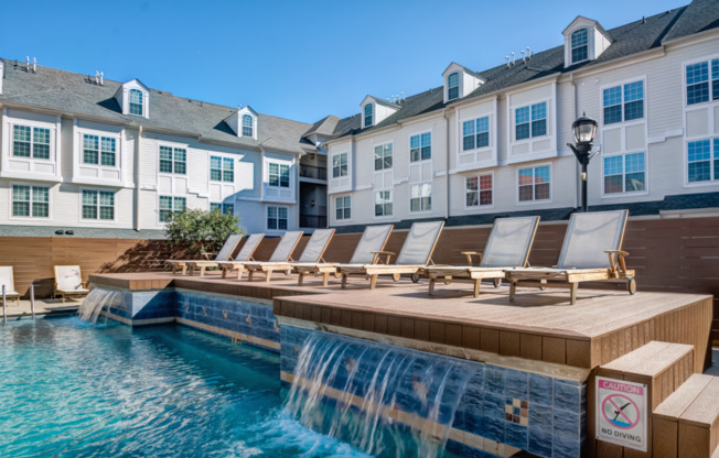 a pool with a waterfall and a row of lounge chairs at Harbor Pointe