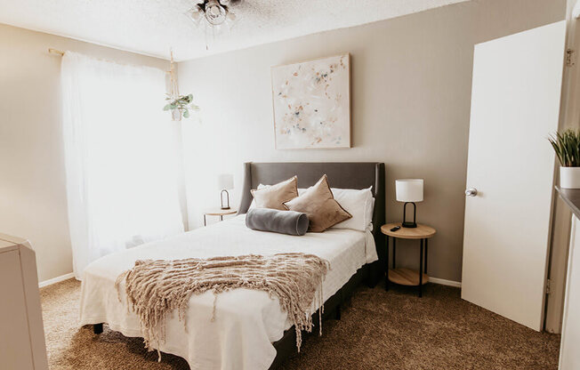 A bedroom with a bed, nightstands, and a painting on the wall.