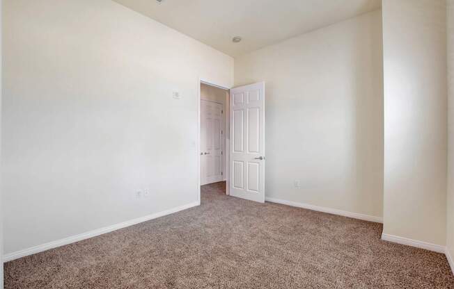 A room with a carpeted floor and a white door.