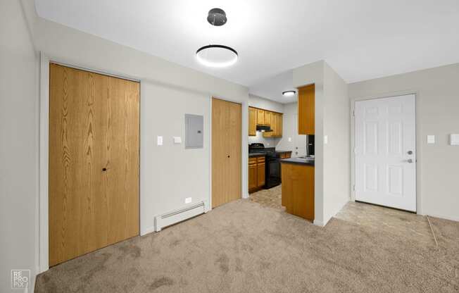 a bedroom with a door to a kitchen and a carpeted floor