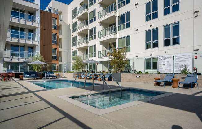 a pool and hot tub overlooked by an apartment building