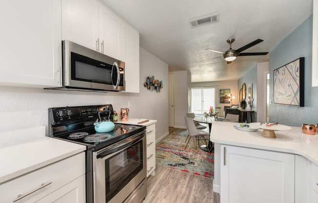 Kitchen with Hardwood Inspired Floor, Oven, Microwave, Stove and White Cabinets