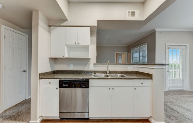 an empty kitchen with white cabinets and a stainless steel dishwasher