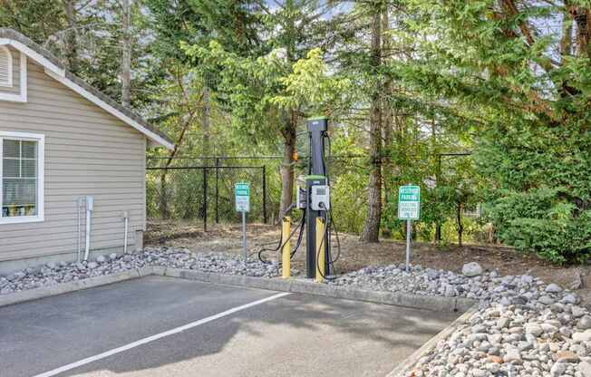 A charging station for electric vehicles with trees in the background at Abbey Rowe Apartments in Olympia, WA