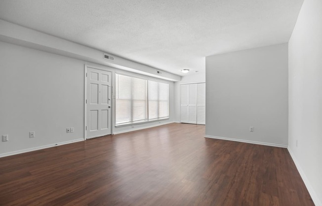 the living room and dining room of an apartment with wood floors and white walls