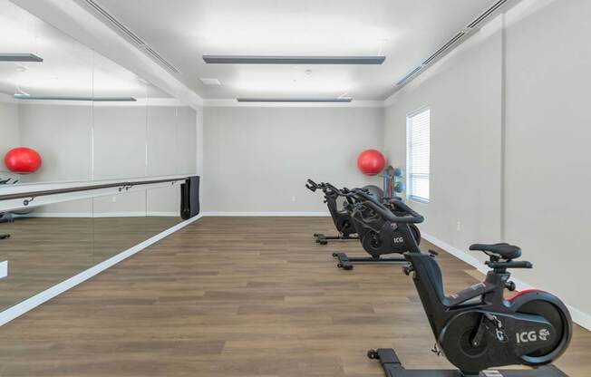 A room with exercise bikes and red balls on the wall.