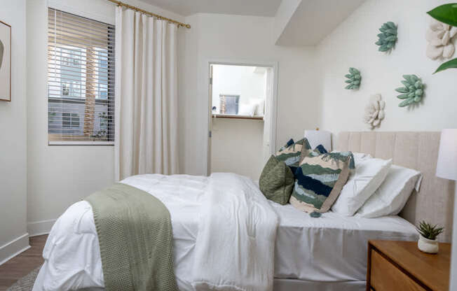 A bedroom with a bed covered in a white sheet and a green blanket.