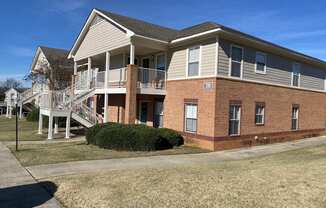the front of a brick house with a porch and stairs