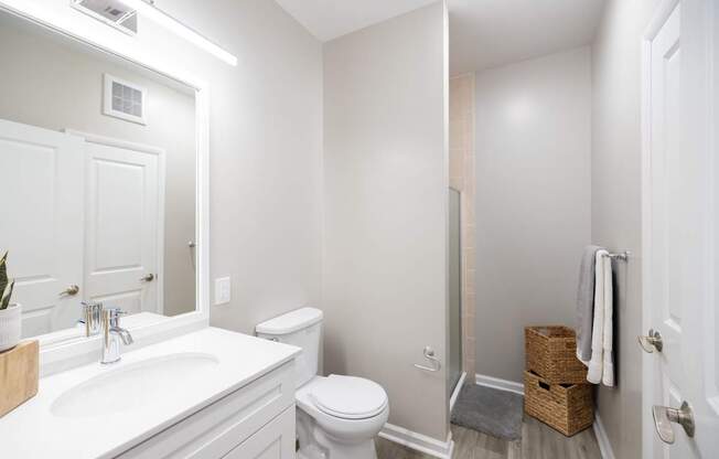A white bathroom with a toilet, sink, and mirror at Harbor Pointe Apartments, New Jersey