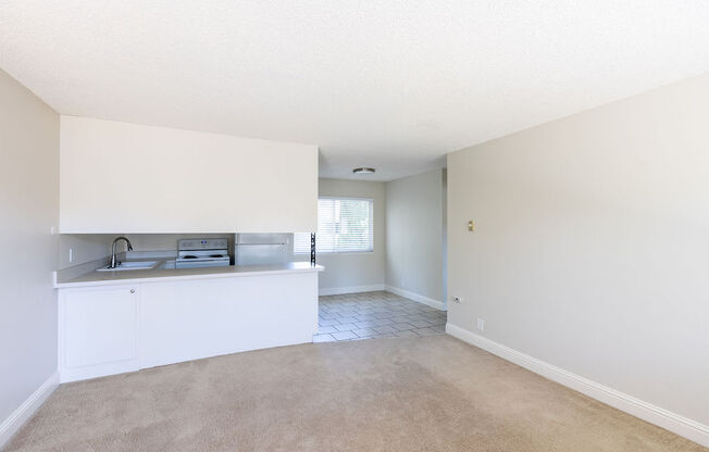 an empty living room and kitchen with a counter and sink