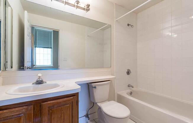 A white toilet sits in a bathroom next to a sink and a bathtub.