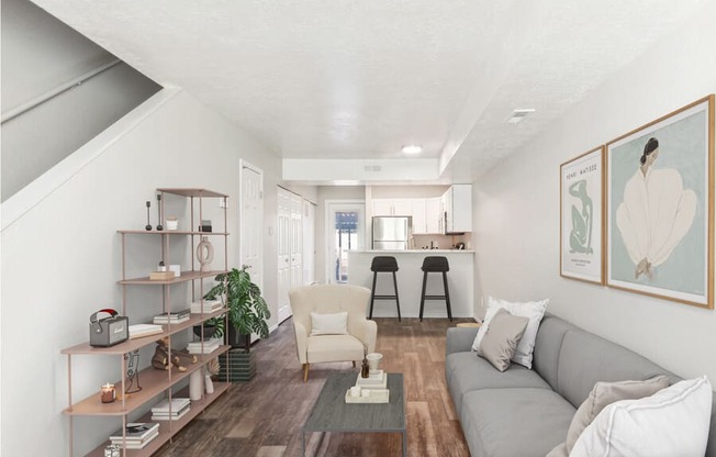 Model living room with a couch and a coffee table and stairs leading up to the 2nd floor.