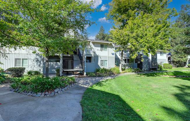 Monte Bello Community grounds with mature tress and landscaping around the building.  Concrete walk path  at Monte Bello Apartments, Sacramento
