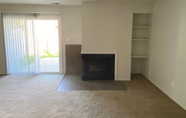 Townhome living room at Ashley Pointe Apartments with a fireplace and a sliding door to patio