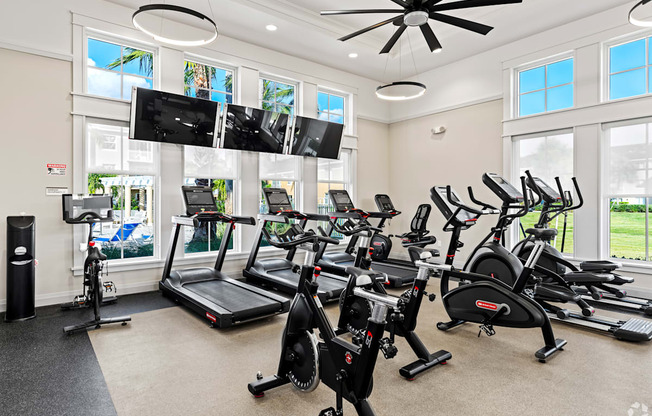 A spacious gym with treadmills, elliptical machines, and a television.