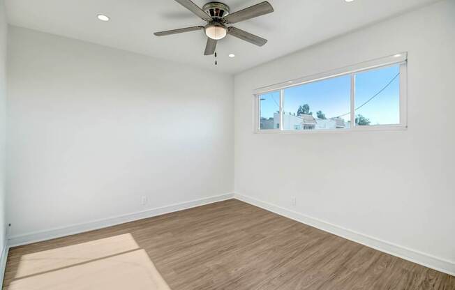 an empty living room with a ceiling fan and a window