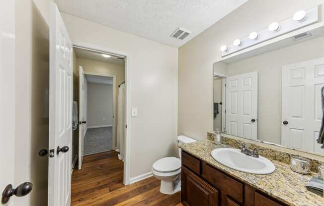 a bathroom with a sink and a toilet and a mirror at Grand Reserve Columbus in Columbus, GA