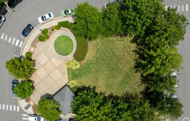 A park with a circular grassy area and a building in the background.