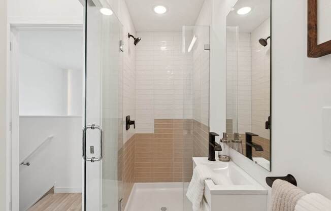 A bathroom with a white sink and a glass shower stall.