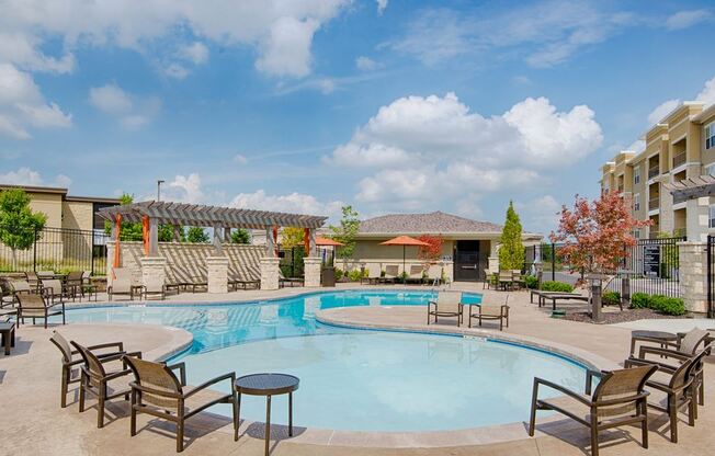 A large outdoor swimming pool surrounded by chairs and tables.