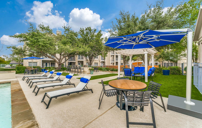 a patio with chairs tables and umbrellas and a pool