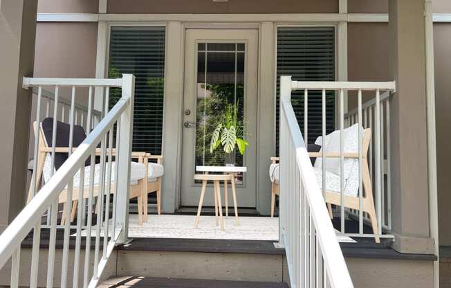 a porch with two chairs and a stool