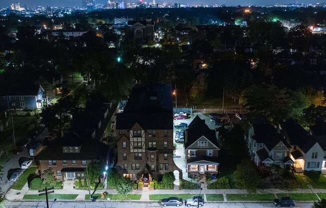 an aerial view of houses at night with the city skyline in the background