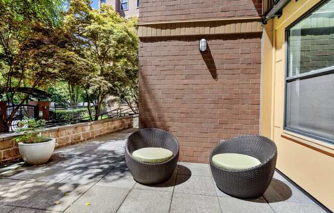 two chairs sit on a patio in front of a brick wall