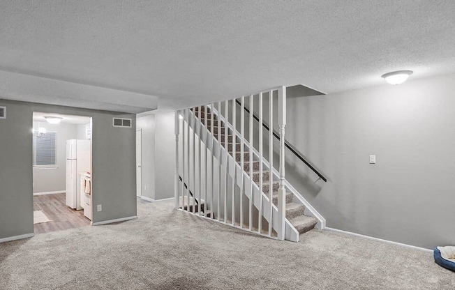 a white carpeted living room with a staircase