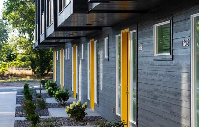 A line of modern houses with grey siding and yellow doors.
