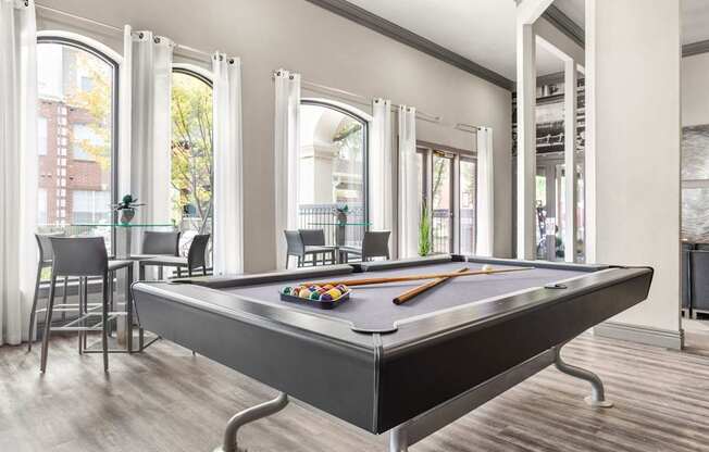 A pool table is in the middle of a room with a lot of windows.